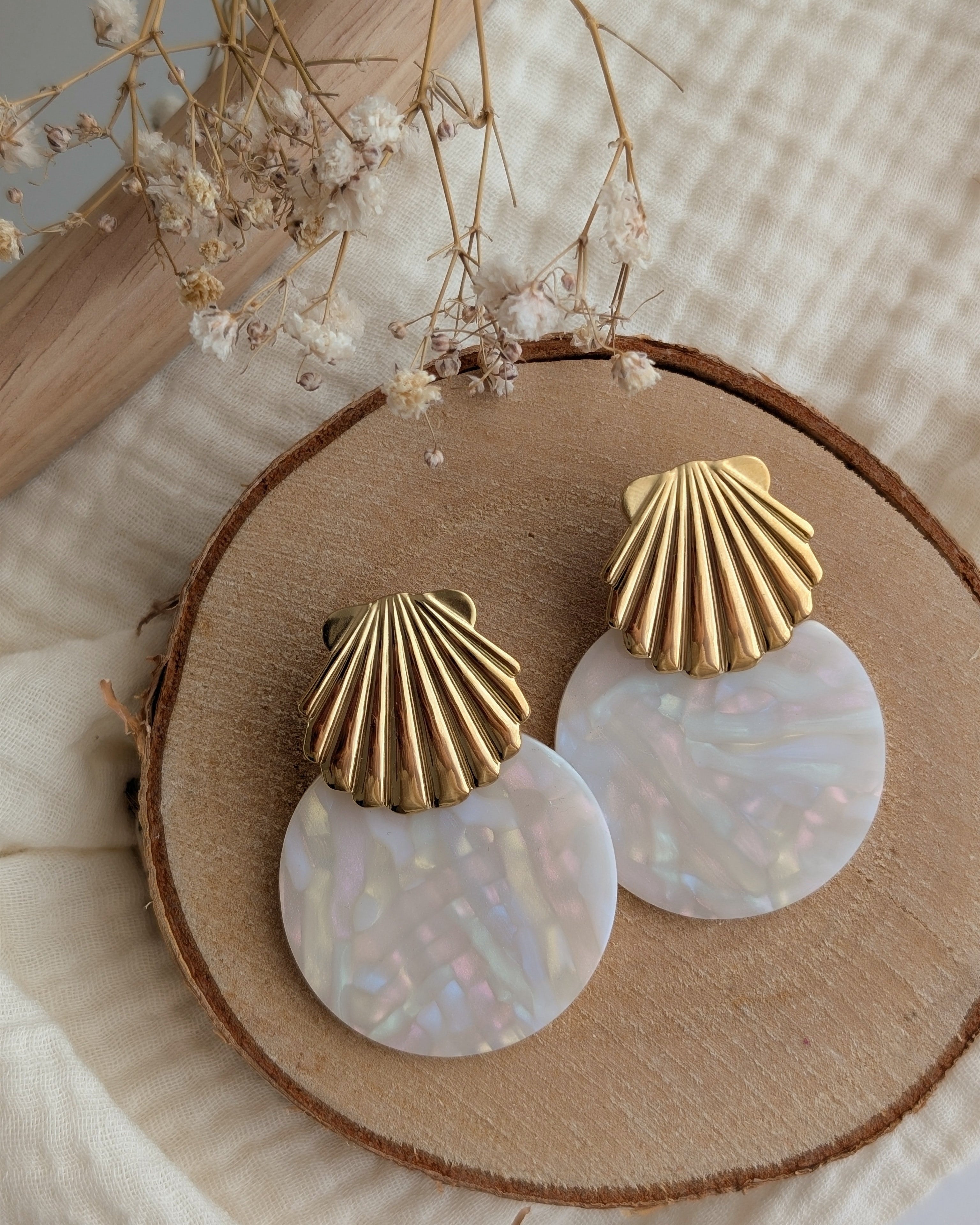 Boucles coquillage Calypso en acier et acétate de cellulose blanc irisé . Posées sur rondin. Création La Tête dans les Nétoiles