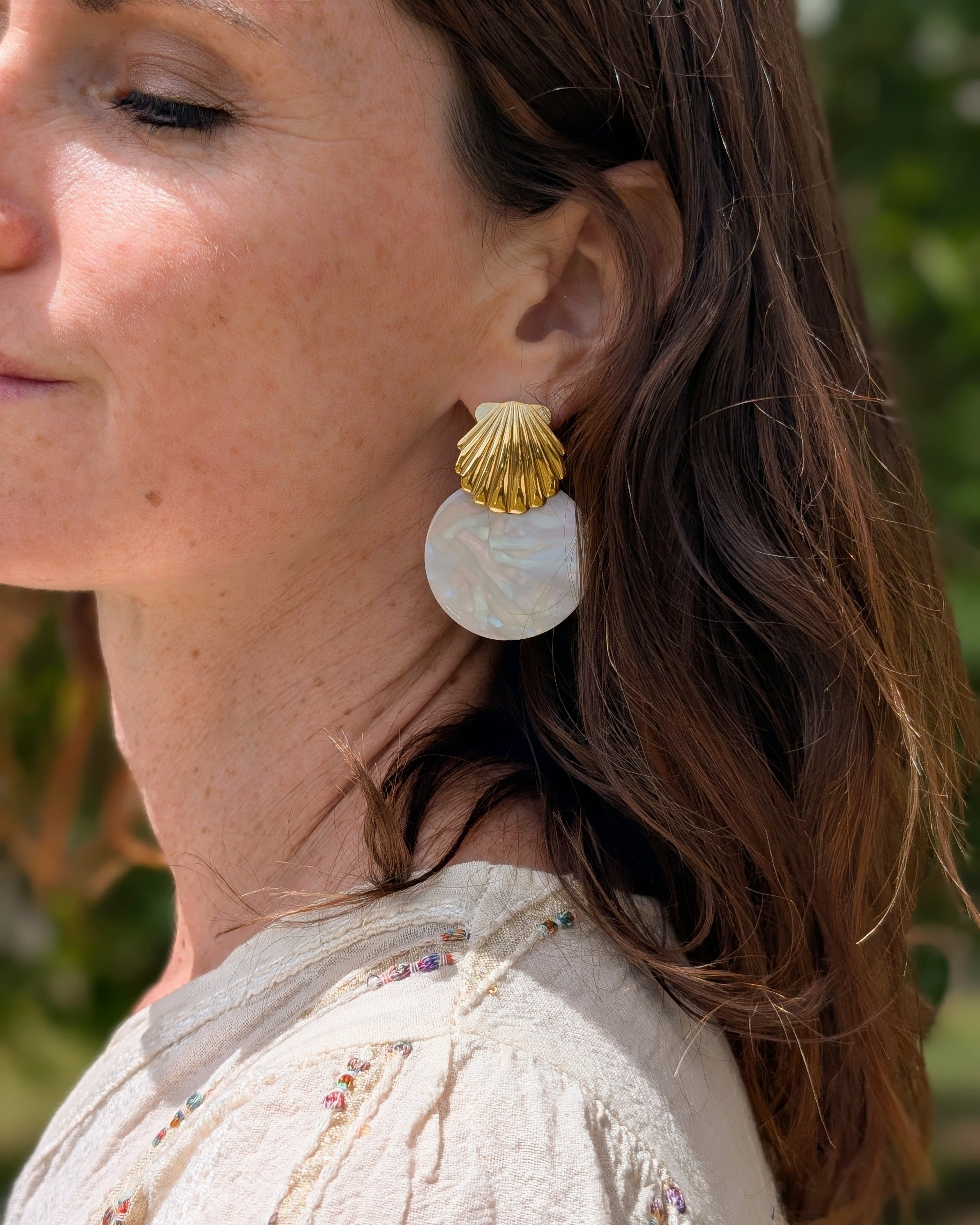 Boucles d'oreilles Calypso coquillage acier et acétate irisé portées par une femme vue de loin. Création La Tête dans les Nétoiles