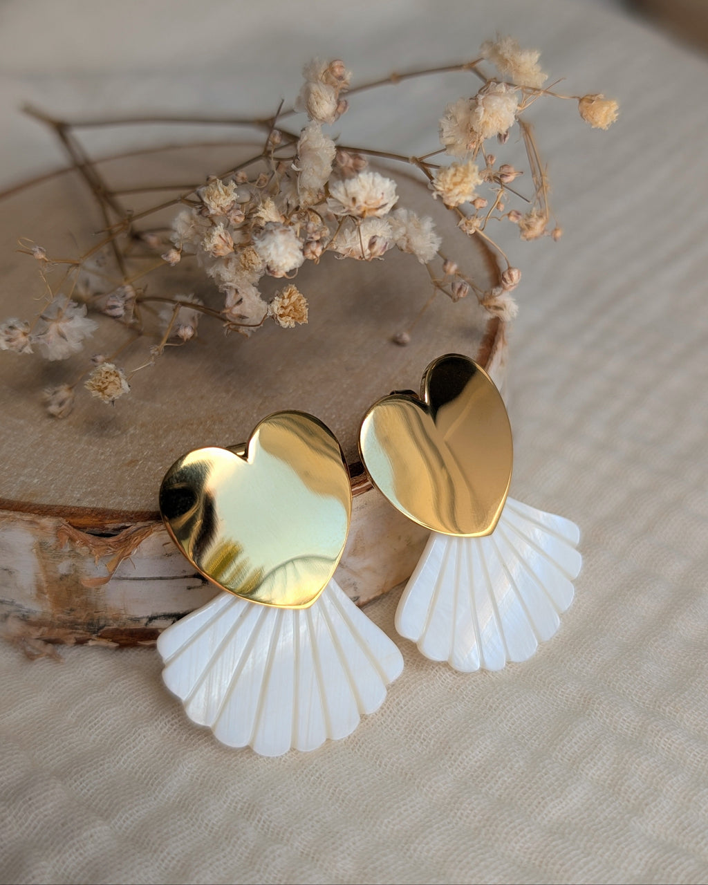 Boucles coeur doré et éventail nacre posées sur gaze de coton et rondin de bois. Créations artisanales La Tête dans les Nétoiles