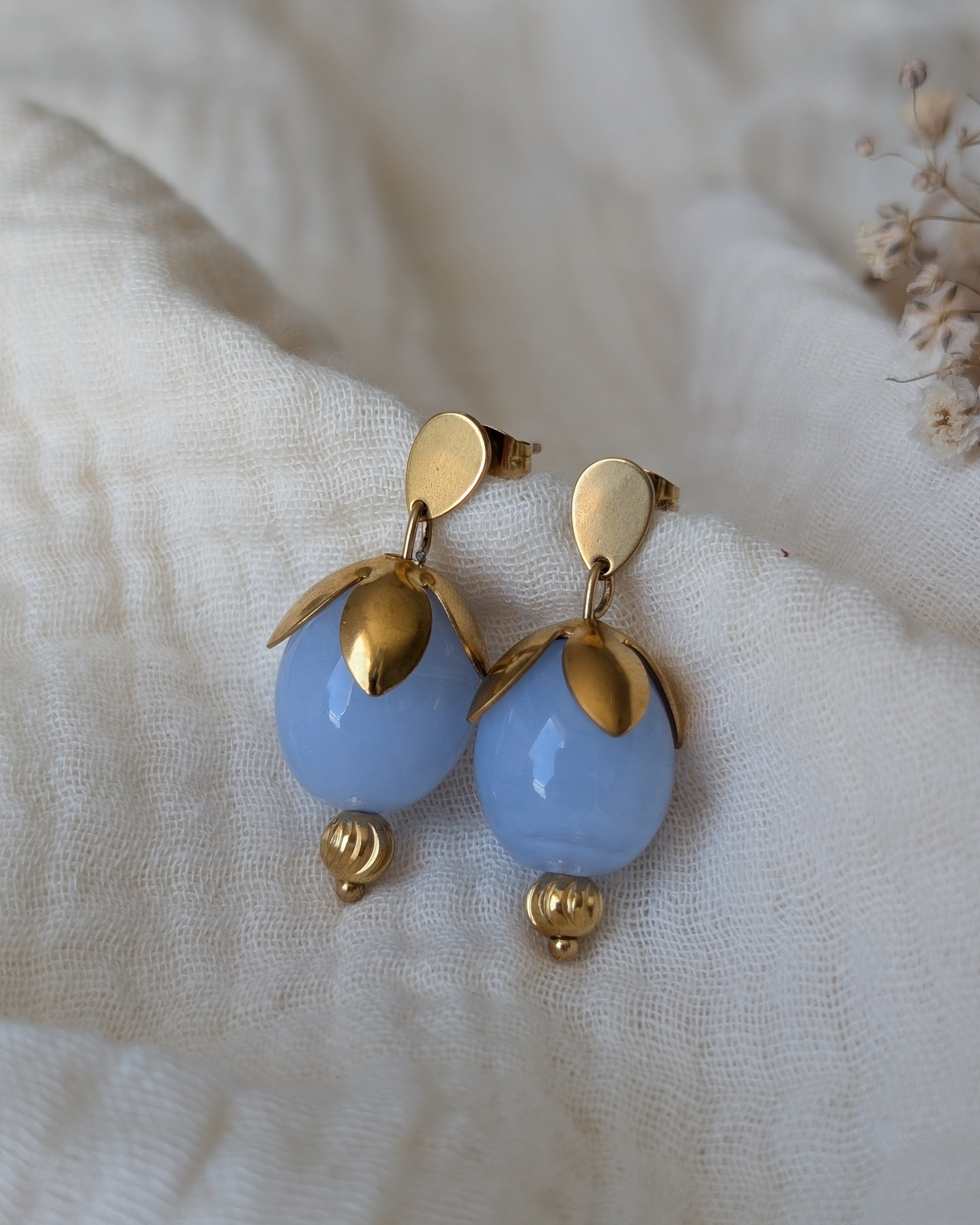 boucles d'oreilles Oliva bleu azur en forme de bourgeon. posées sur gaze de coton. Créations artisanales La Tête dans les Nétoiles