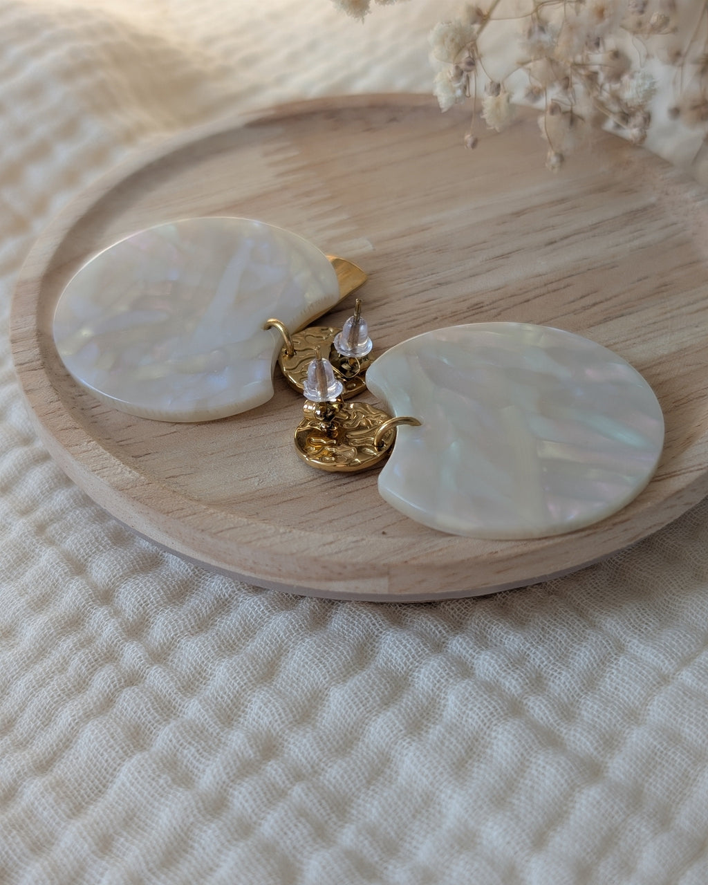 Boucles d'oreilles Zéline vue de dos zoom sur les fermoirs. Posées sur support en bois. Création La Tête dans les nétoiles.