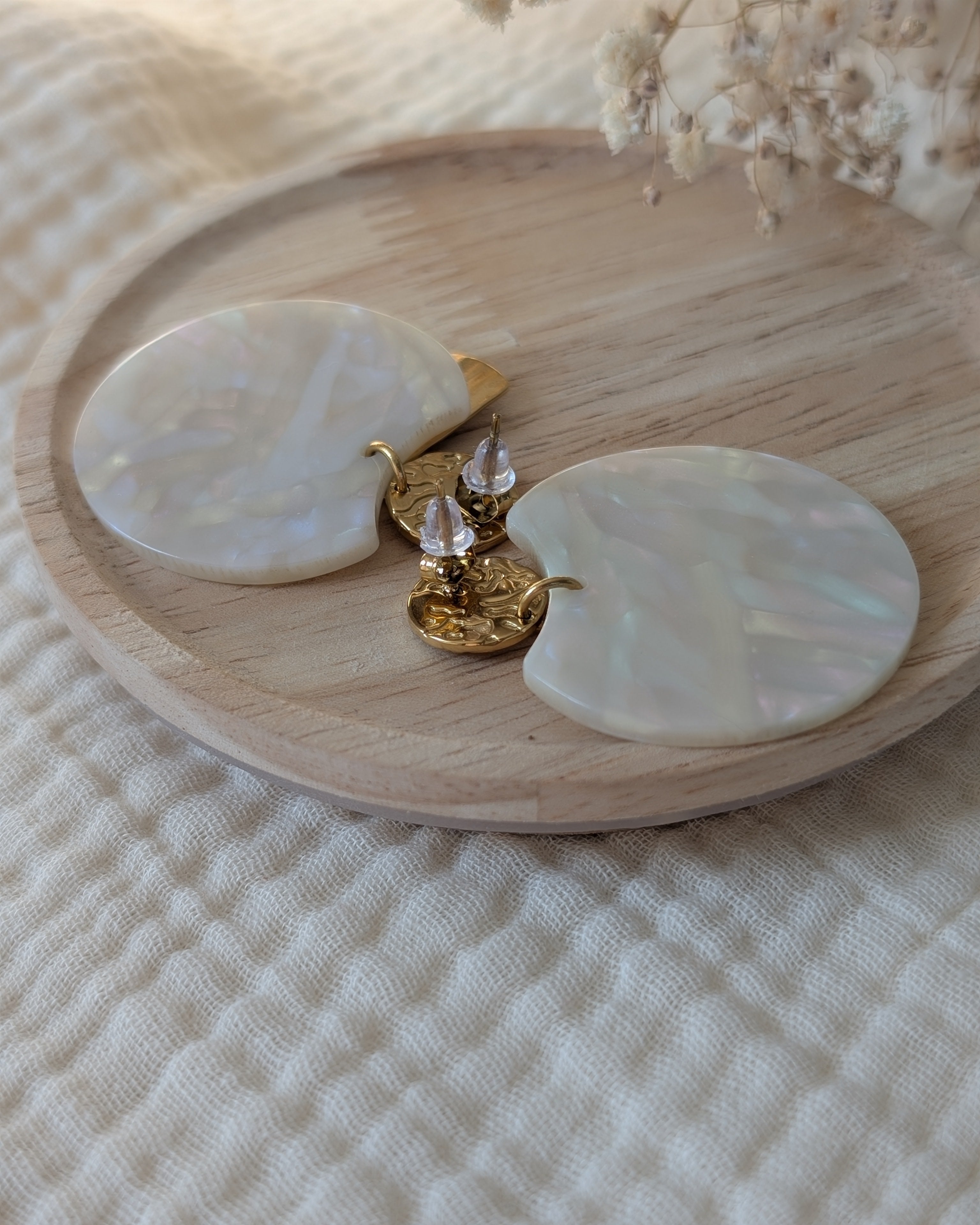 Boucles d'oreilles Zéline vue de dos zoom sur les fermoirs. Posées sur support en bois. Création La Tête dans les nétoiles.