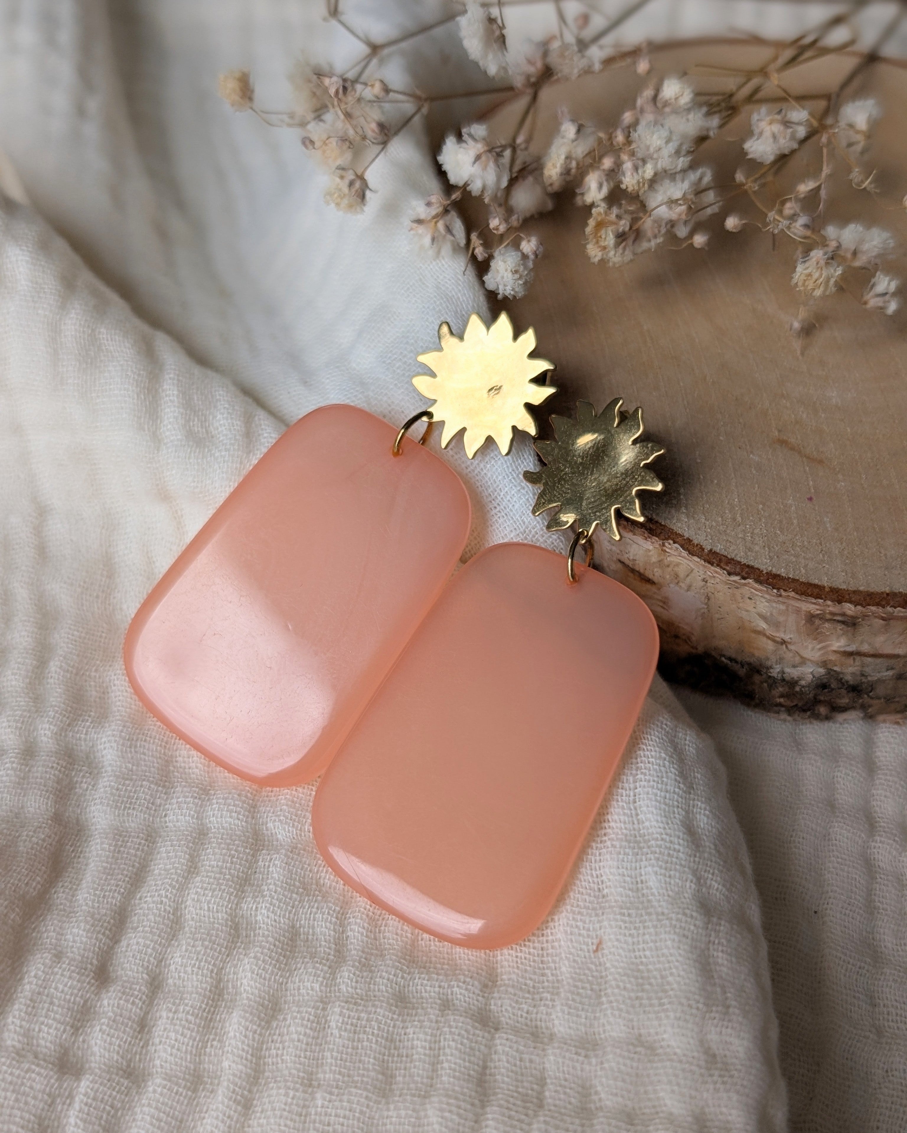 boucles pendantes alba soleil et rectangle resine peche orange posées sur gaze de coton et rondin de bois. Créations La Tête dans les Nétoiles