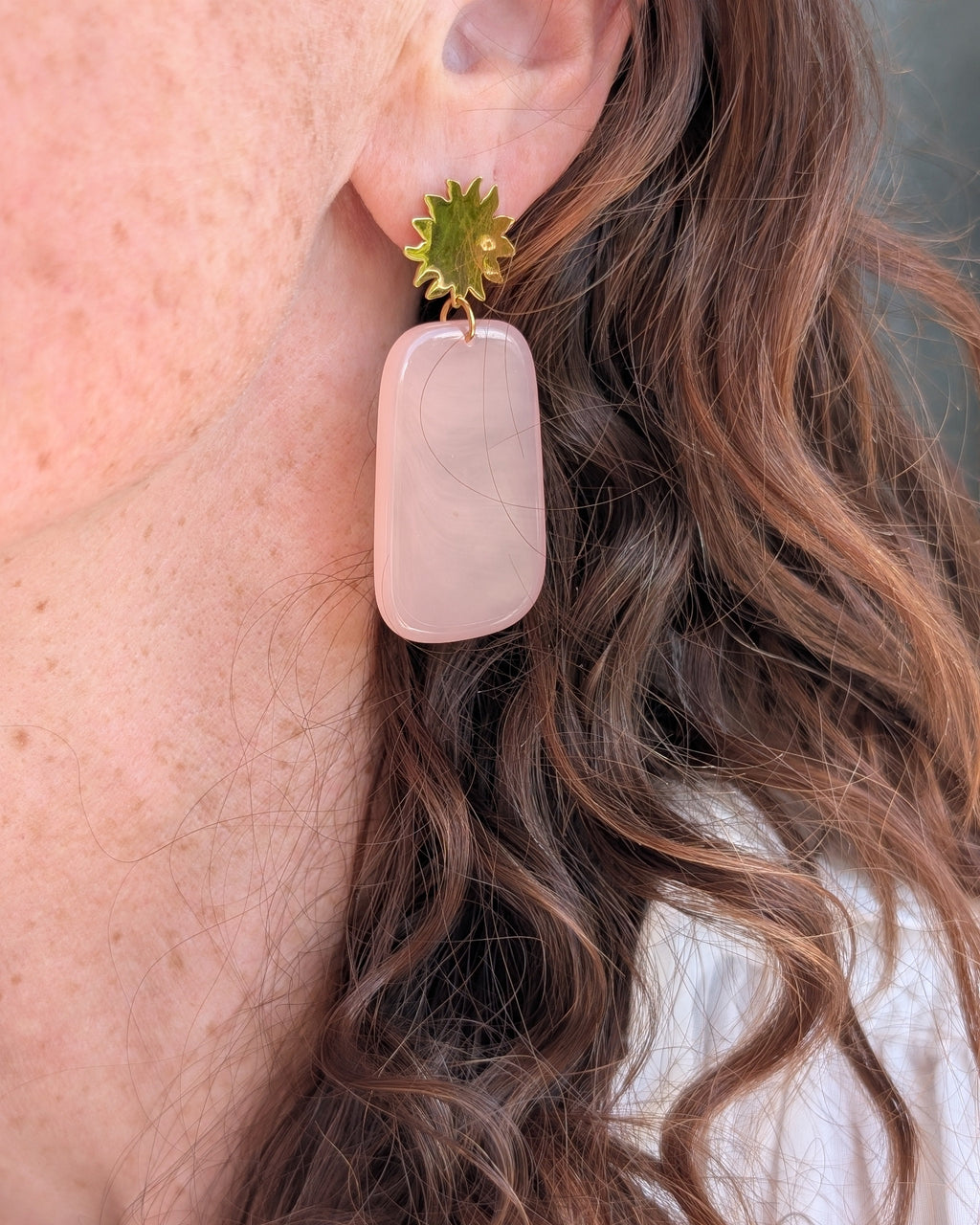 Boucles pendantes Alba puces soleil et pendentif rectangle résine rose poudré. Porté par une femme. Créations artisanales La Tête dans les Nétoiles