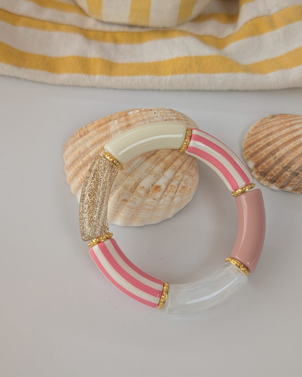 Bracelet perles tube à rayures rose photo en gros plan. et perles intercalaires dorées. Créations La Tête dans les Nétoiles