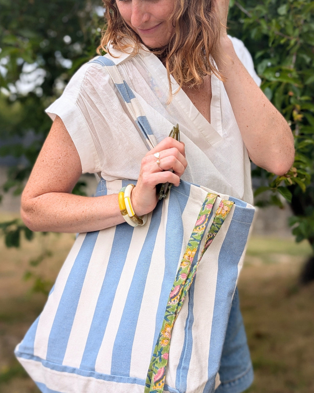 Duo de bracelets perles tube à rayures jaune portés par une femme avec sac et cordon de telephone. Créations artisanales La Tête dans les Nétoiles