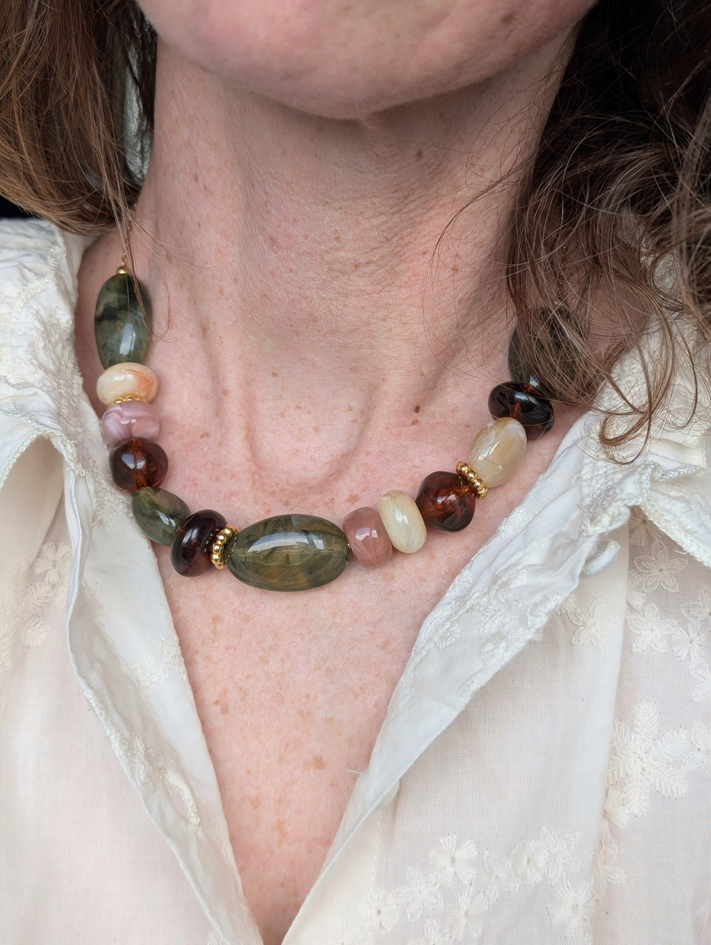 Collier GABIE porté par une femme. Perles irrégulières en résine aux nuances de vert et d'ambre . Création artisanale La Tête dans les Nétoiles