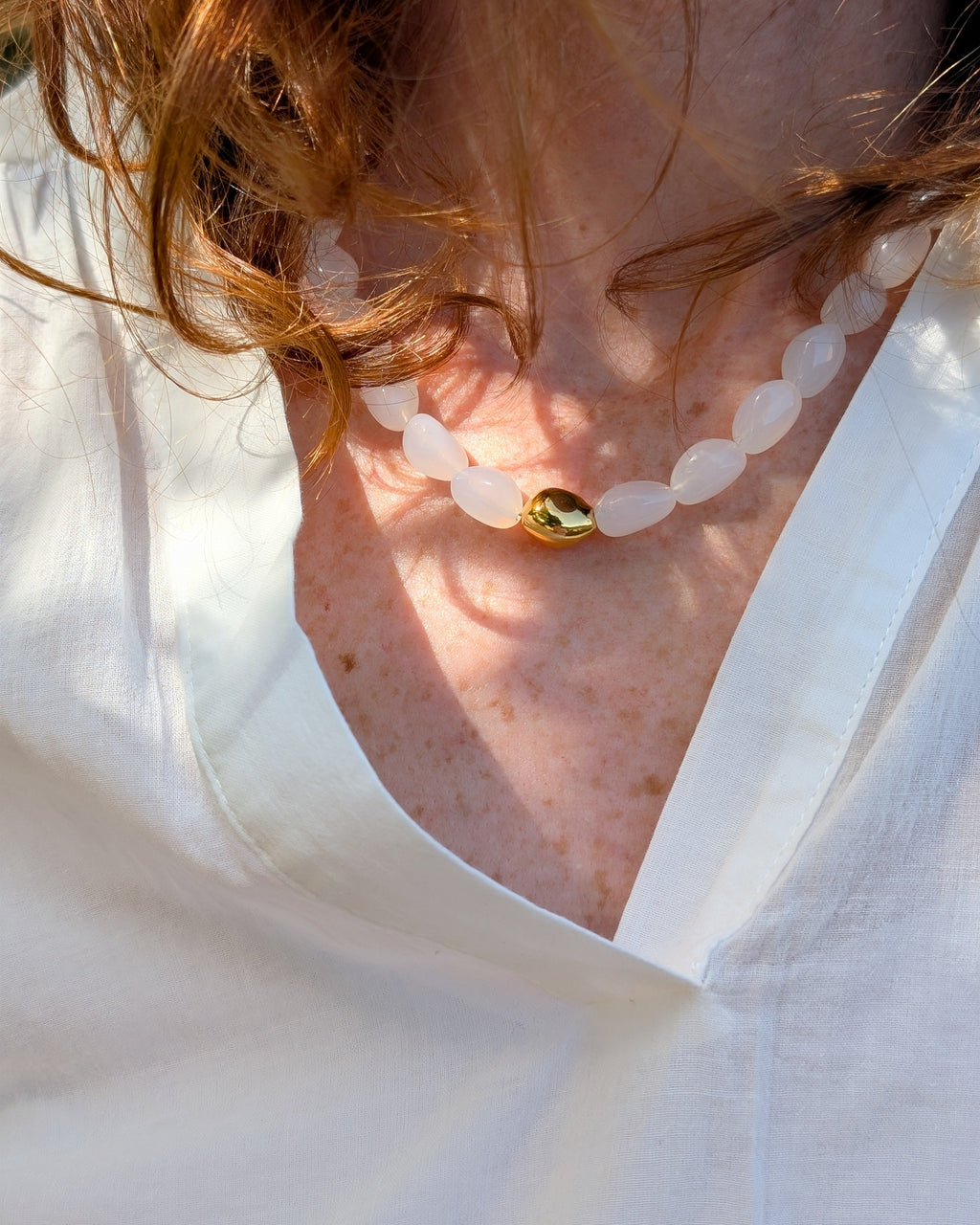 Collier Louison coloris blanc opale porté par une femme photo en gros plan. Création La Tête dans les Nétoiles. 