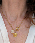 Collier NAHEE chaine maille pendentif coquillage et perle résine beige. Porté par une femme avec une blouse blanche. Créations artisanales La Tête dans les Nétoiles