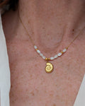 collier Néri pendentif ammonite en acier inoxydable doré porté par une femme. Créations artisanales La Tête dans les Nétoiles 