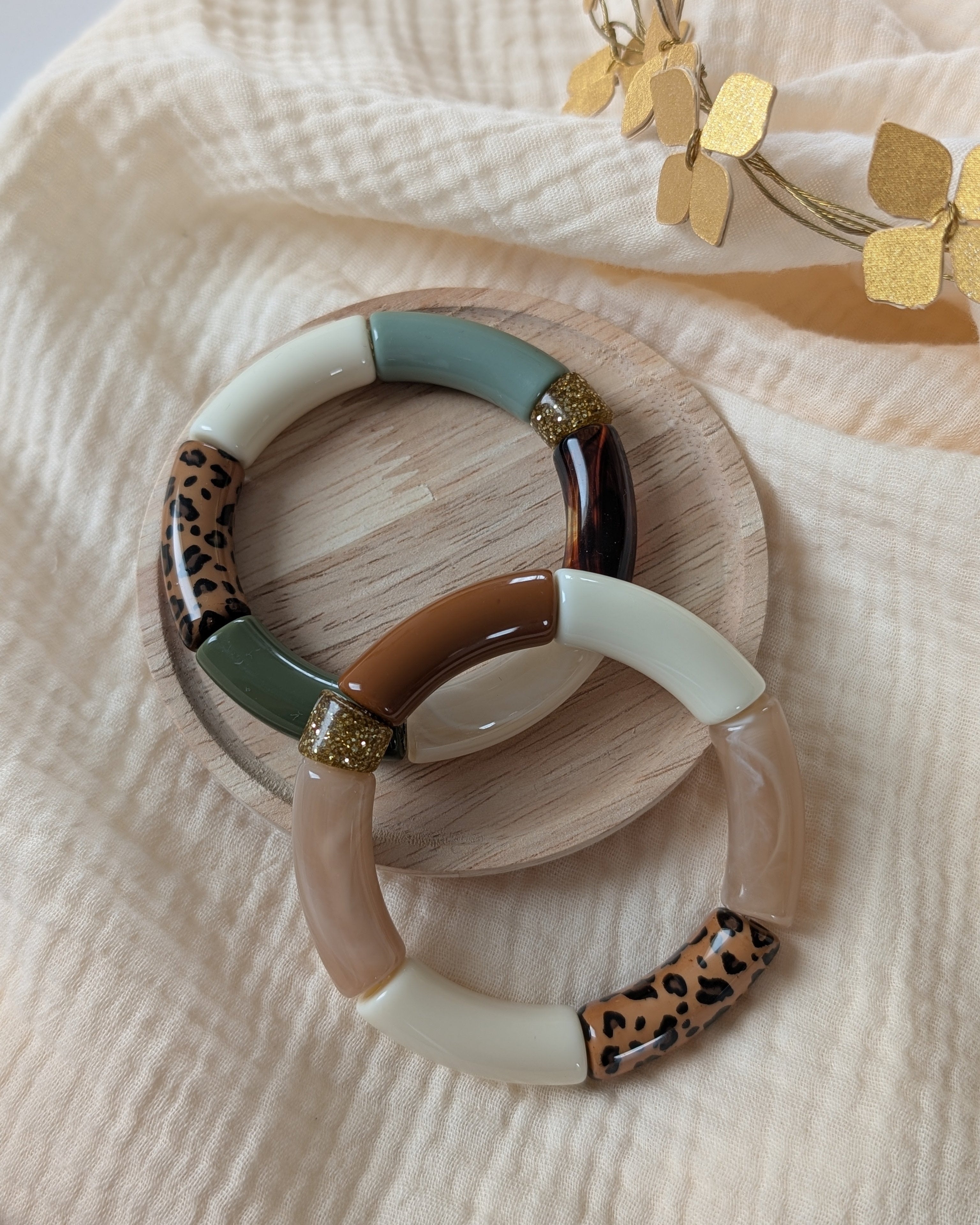 duo bracelet perles tube Mona leopard_en_vert_et_tons narurel posé sur support en bois et gaze de coton écru. Création La Tête dans les Nétoiles