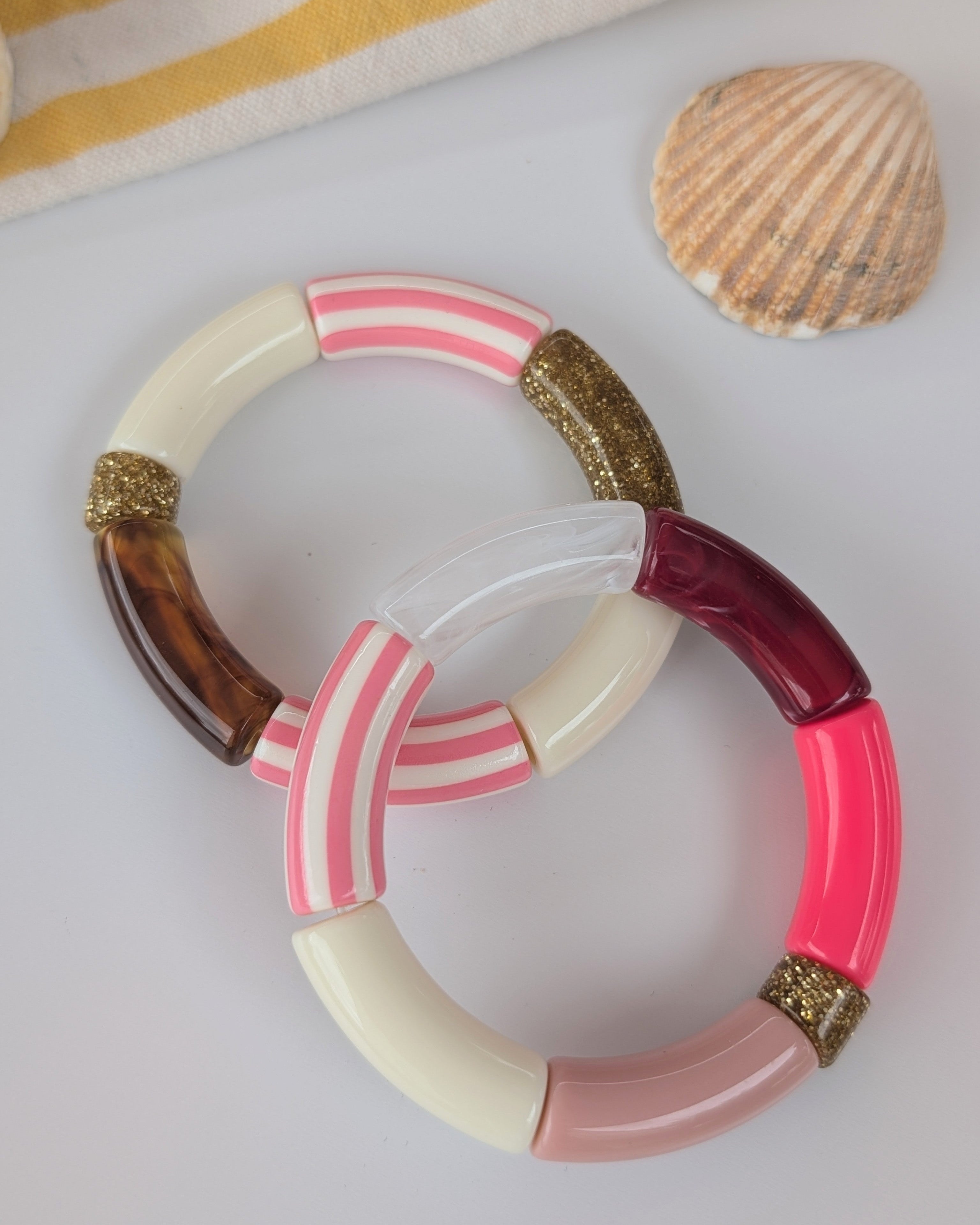Duos de bracelets perles tube Mona rose à rayures. Posés sur table mise en avant du coloris rose corail bordeaux rose. Créations artisanales La Tête dans les Nétoiles