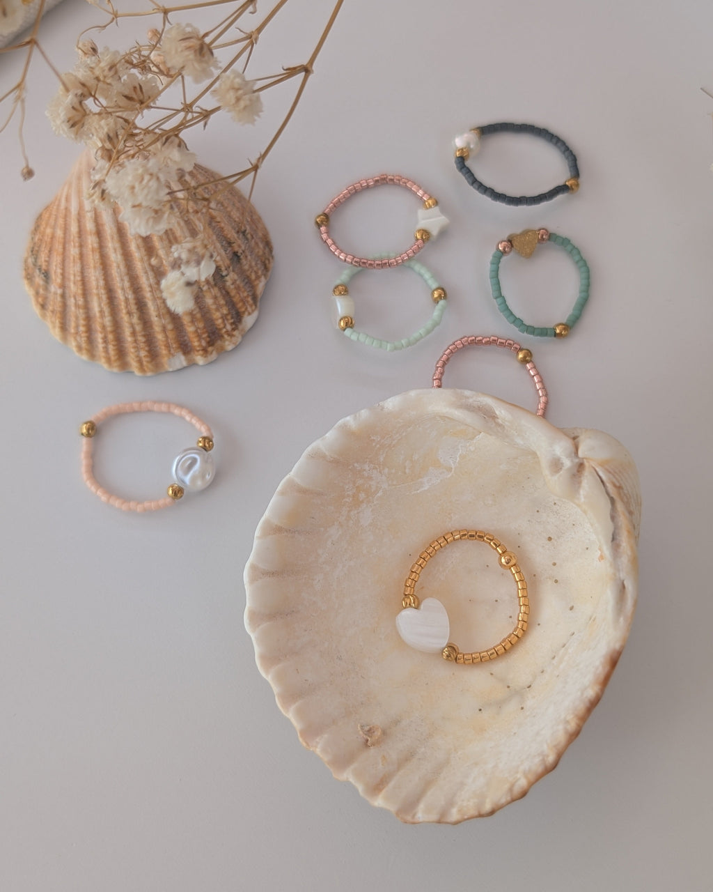 ensemble de bagues perles miyuki et nacre, et perles de culture. Posées sur des coquillages. Créations artisanales La Tête dans les Nétoiles