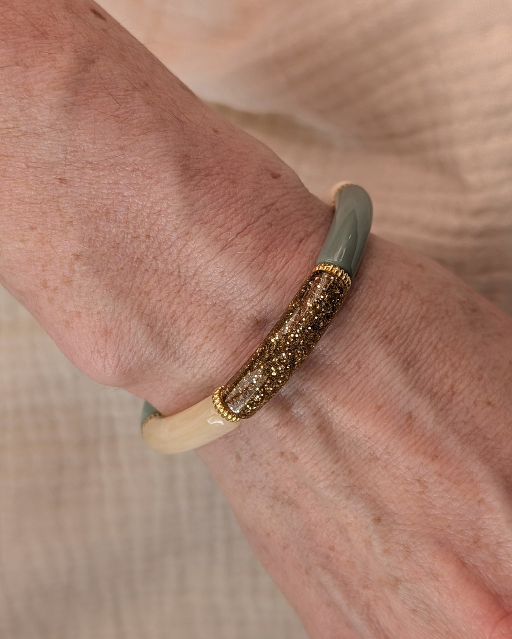 Gros plan bracelet Lison perles tube vert sauge marbré glitter doré et  perles intercalaires dorées de haute qualité. Créations La Tête dans les nétoiles. Porté au poignet d'une femme