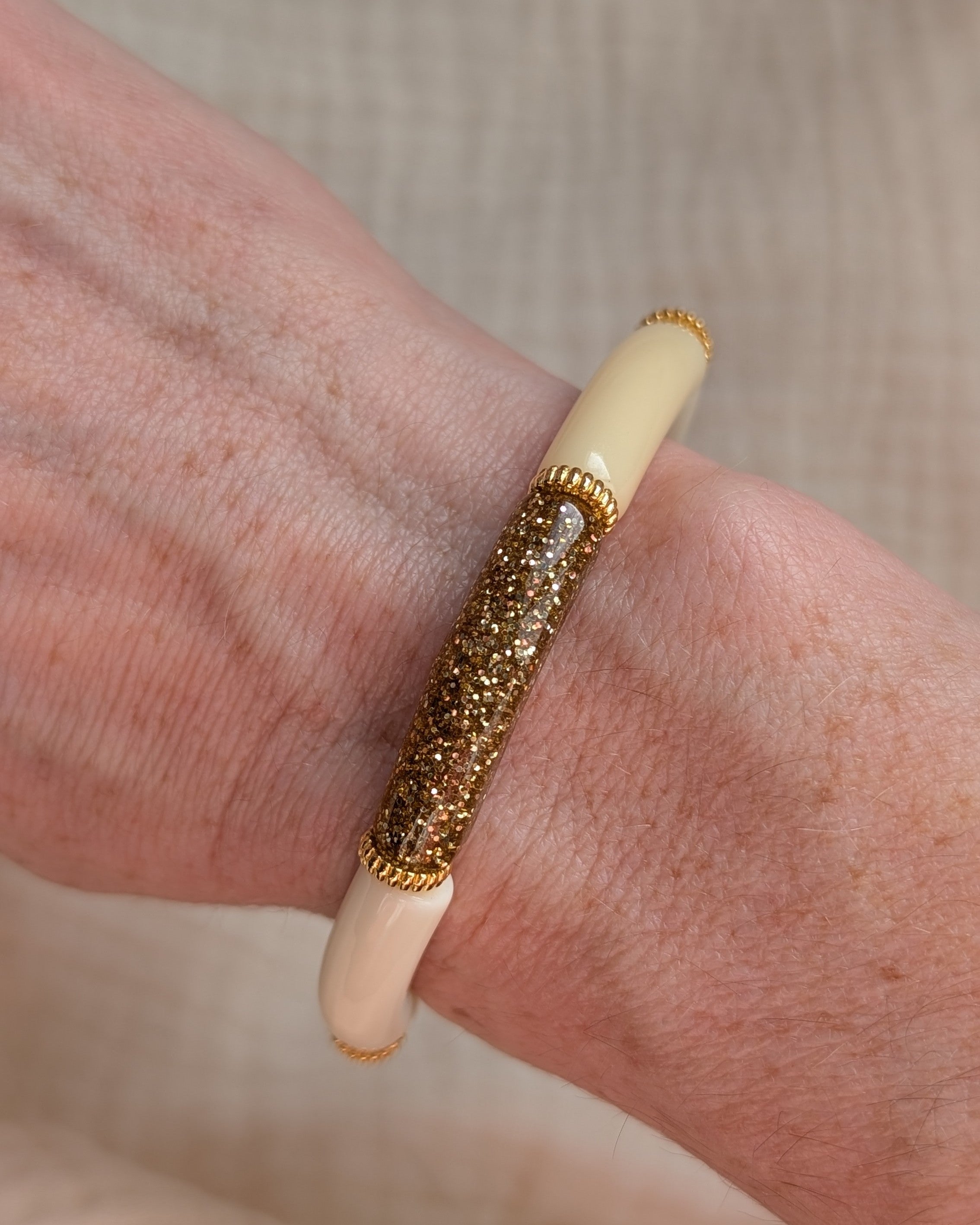 Bracelet perles tube jaune pastel et gros plan sur une perle tube glitter. Porté au poignet d'une femme;
