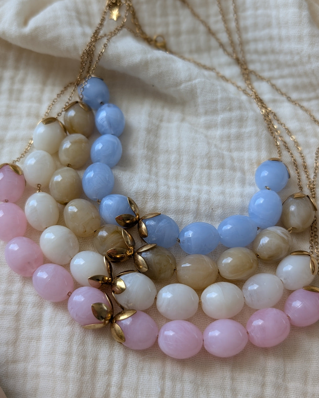 Les 4 coloris du collier perles résine Olivia, bleu azur, rose poudré, blanc et beige marbré. Créations Artisanales La Tête dans les Nétoiles