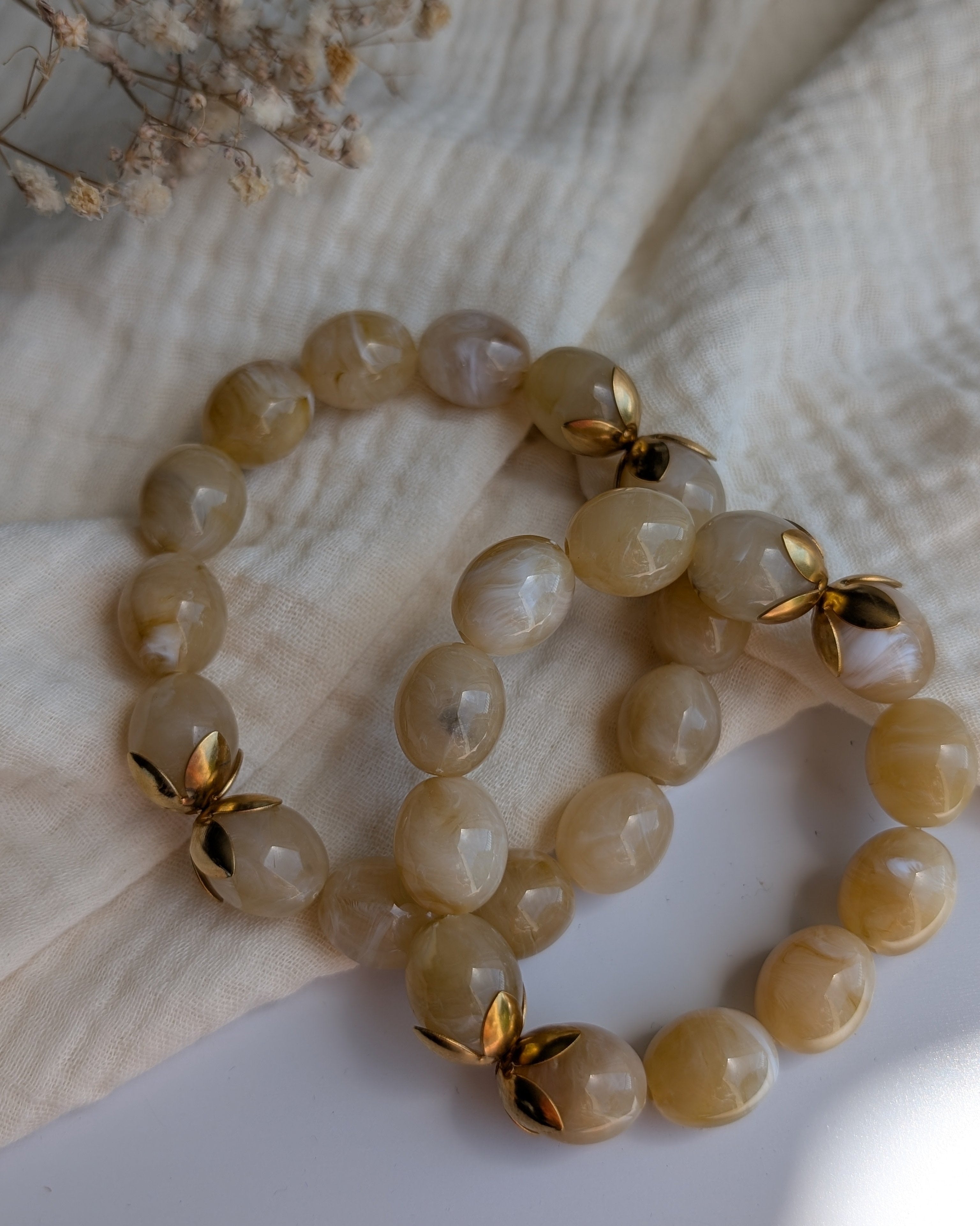 Les deux tailles de bracelets Olivia perles en résine beige marbré. posés sur gaze de coton. Créations artisanales la Tête dans les nétoiles