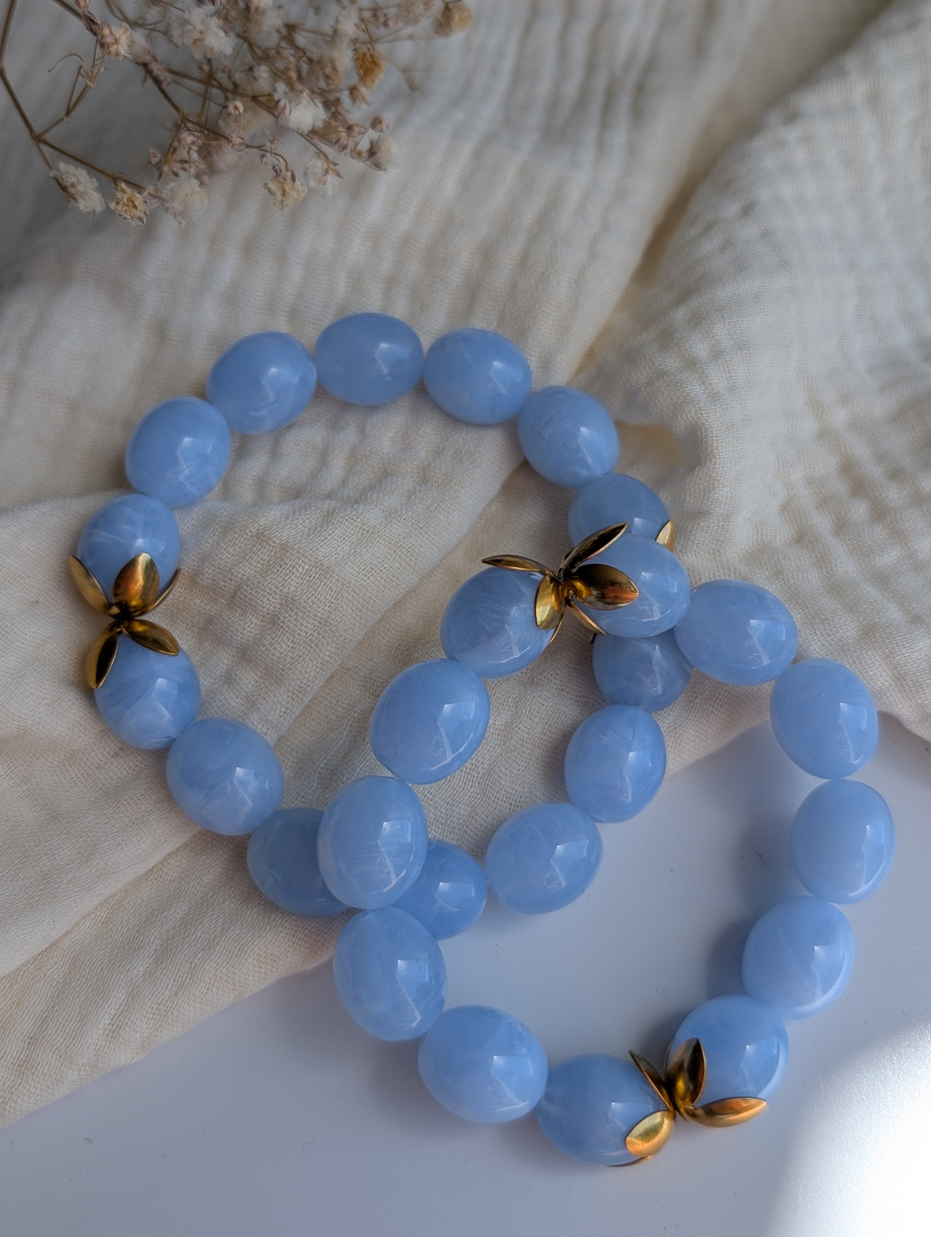 Les deux tailles de bracelets Olivia bleu azur posés sur de la gaze de coton. Créations artisanales La Tête dans les nétoiles