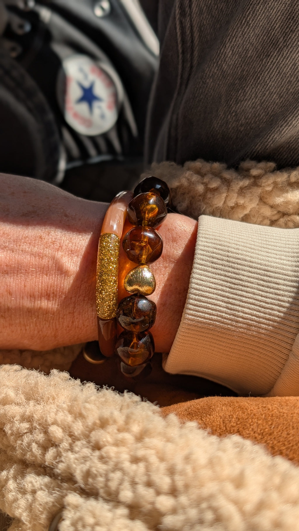 Bracelet Adèle perle en résine caramel et coeur doré. Porté par une femme.