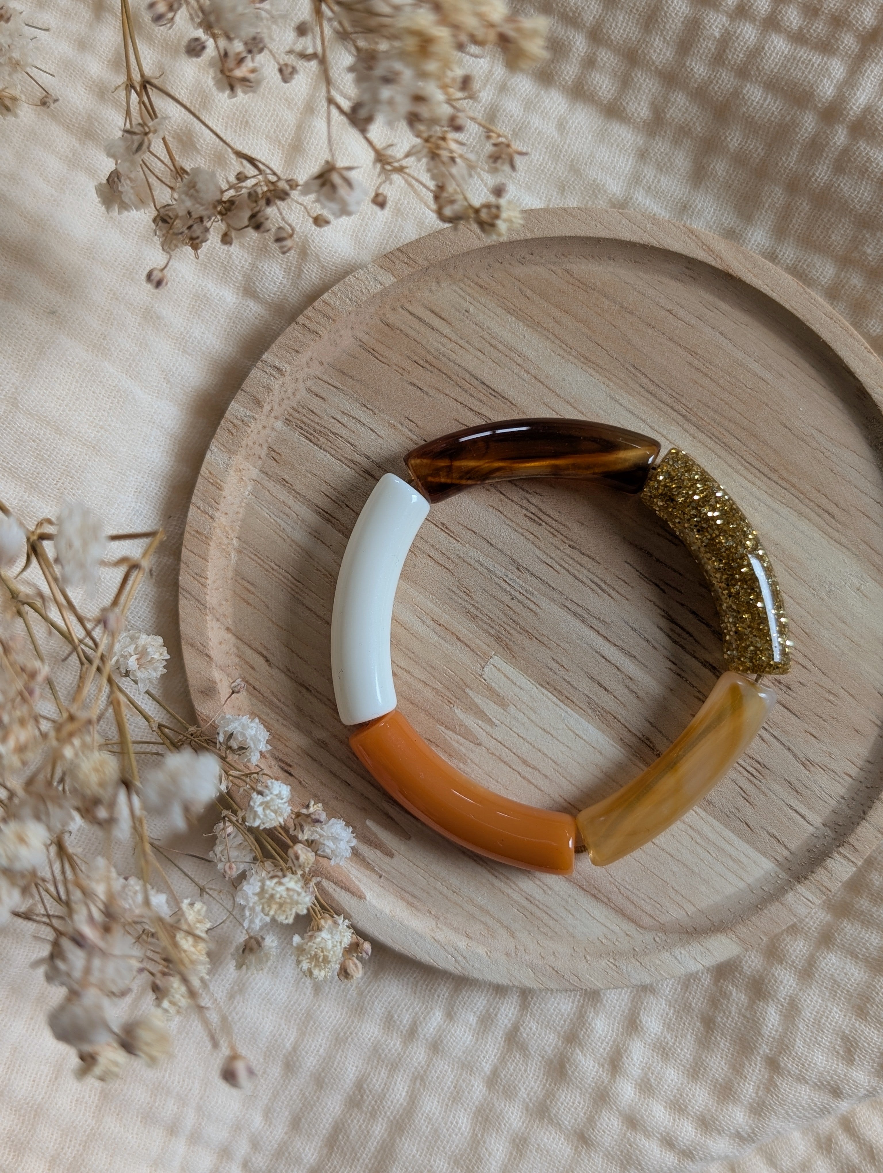 Bracelet enfant perles tubes dans les tons ambrés orange sur support en bois 