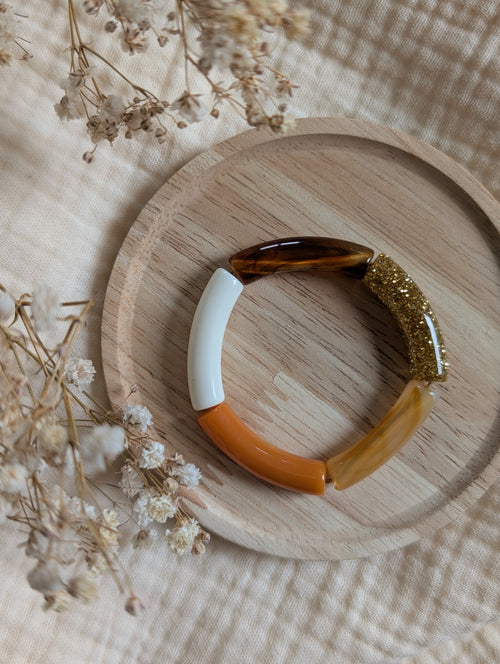 Bracelet enfant perles tubes dans les tons ambrés orange sur support en bois 
